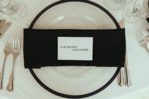 A black napkin placed on a black and white charger plate.
