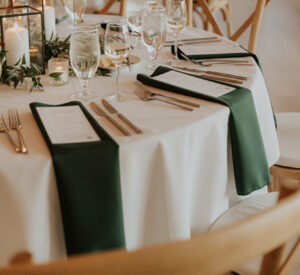 Simple green napkin folds on a wedding reception table.