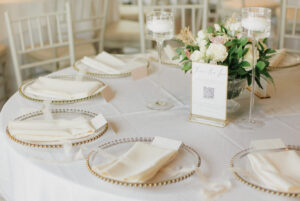 Cream napkins placed on gold beaded charger plates for a wedding reception tablescape.