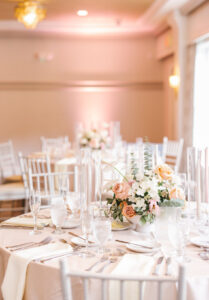 White cloth napkins laid on a pink reception table.