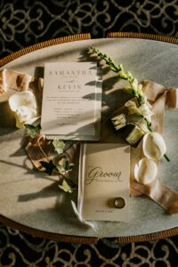 Neutral Colored Wedding Flat Lay and Invitation with Pink Ribbon and Greenery