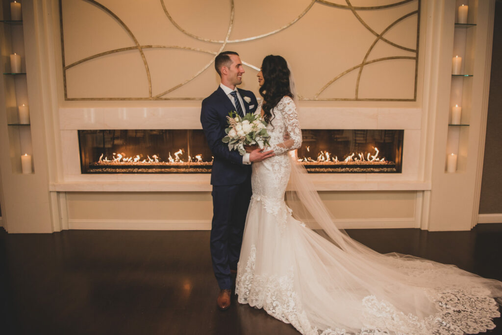 The Villa – Grand Ballroom | Bride and Groom Standing in Front of the Fireplace in the Grand Ballroom at The Villa in East Bridgewater, Massachusetts