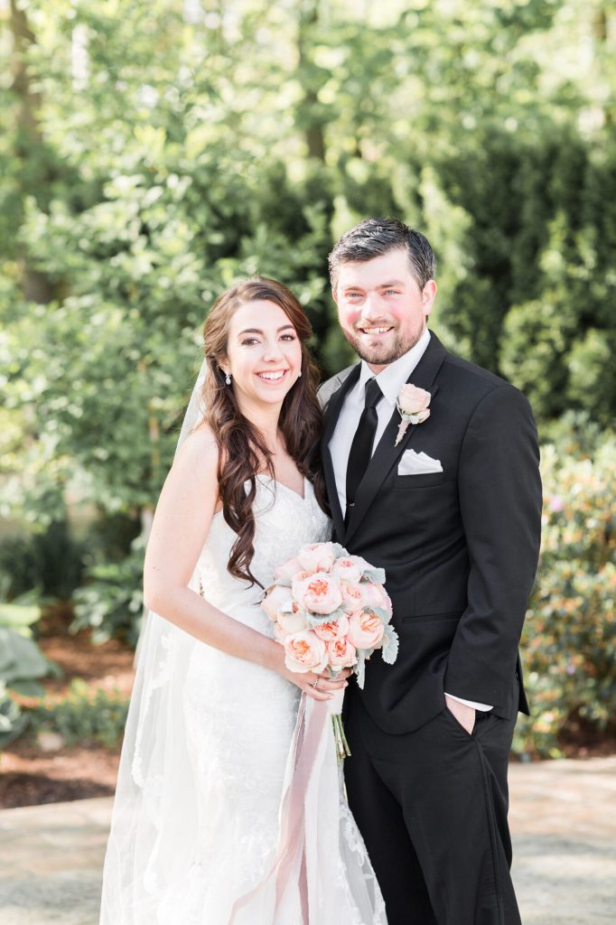 Bride and groom smiling together with her blush peony bouquet.