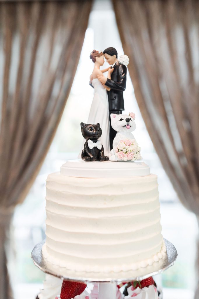 White buttercream cake topped with a couple figurine and two small dog figures.