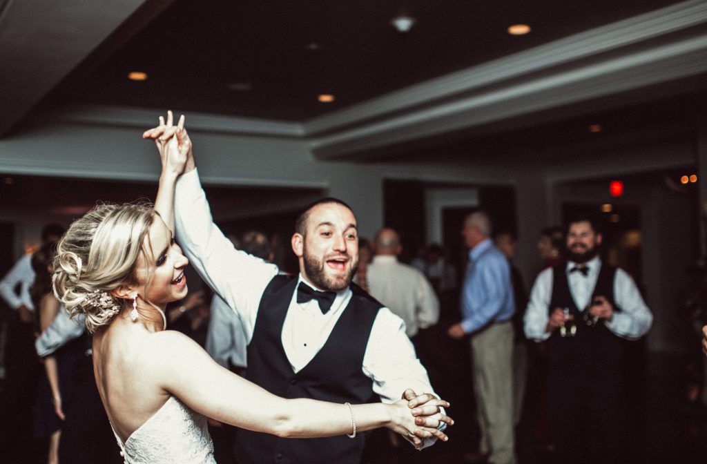 Bride and groom dancing energetically as guests watch the reception floor.