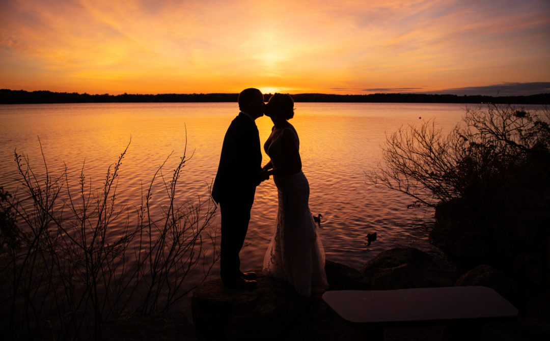 bride and groom kissing at sunset
