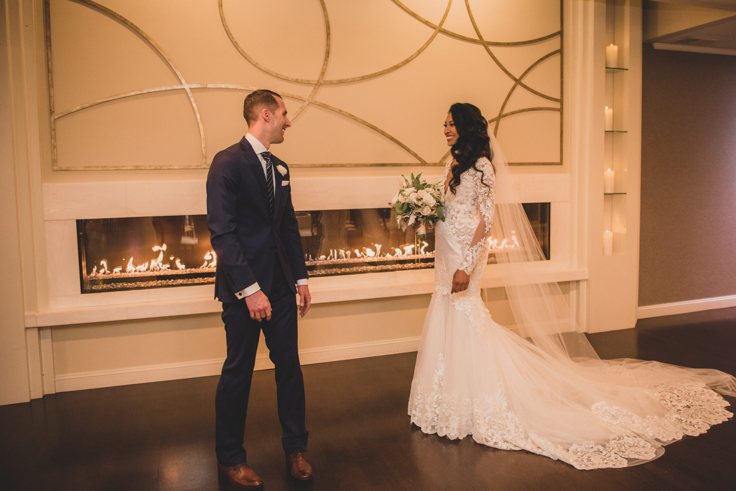 Bride and Groom Standing in Front of The Villa's Fireplace at Their Fall Wedding
