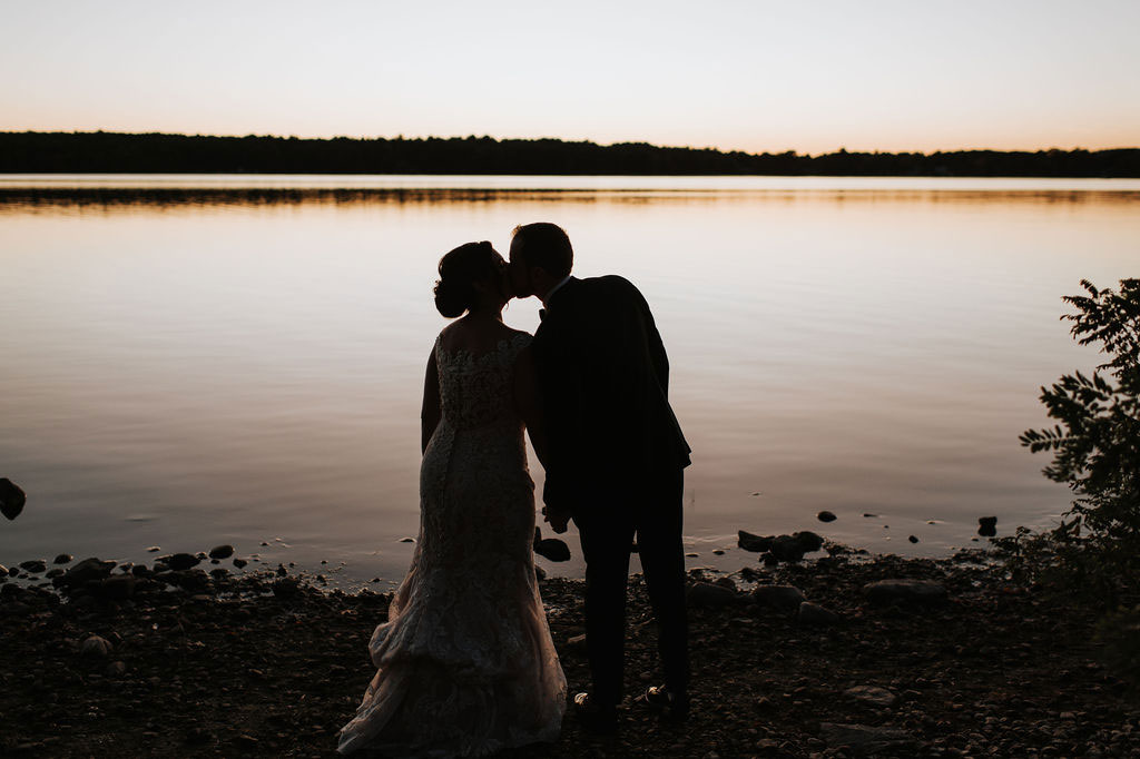bride and groom kissing at sunset