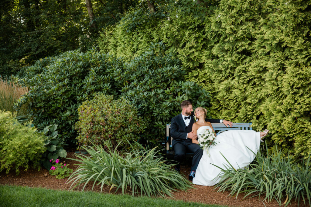 Bride and Groom Sitting on Bench on Avenir's Landscaped Grounds