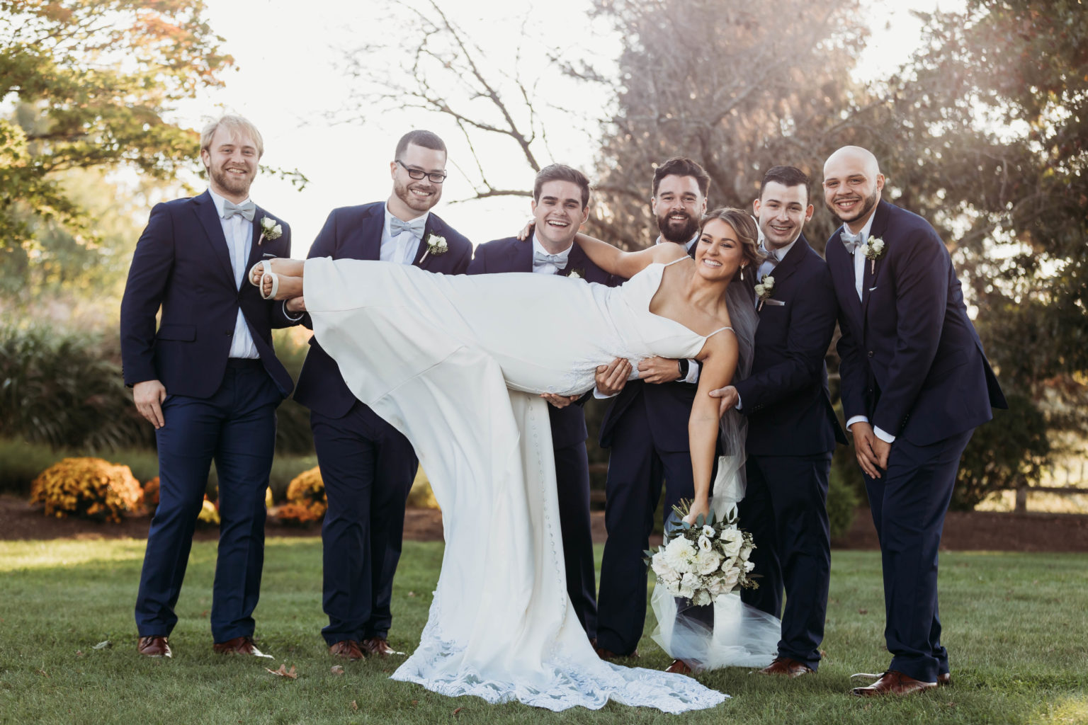 Wedding party pose with groomsmen lifting bride