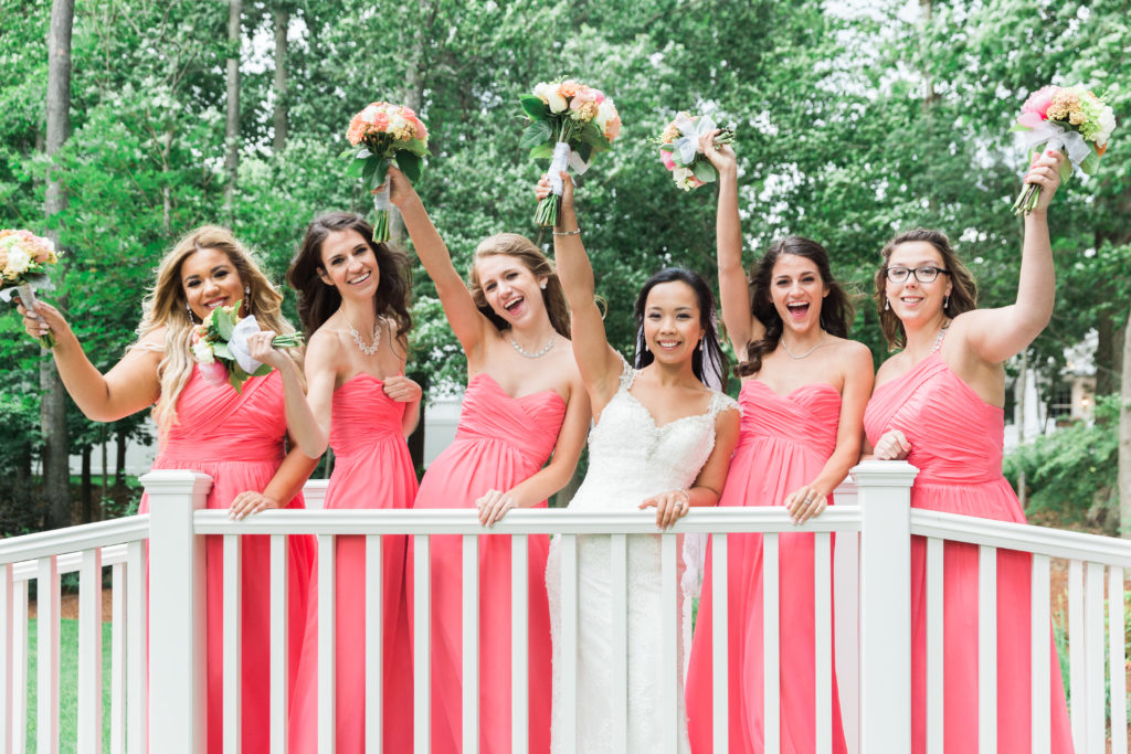Bride and bridesmaids smiling on bridge in outdoor wedding ceremony