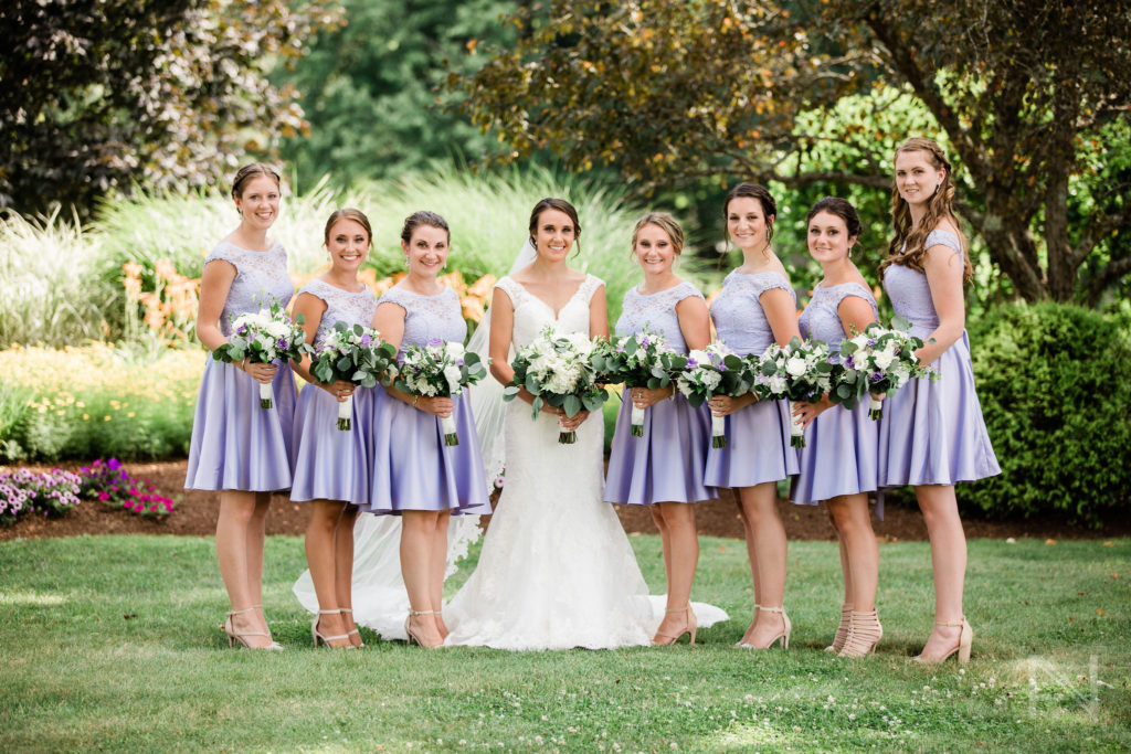 Bride and bridesmaids smiling on lawn in outdoor summer wedding in New England