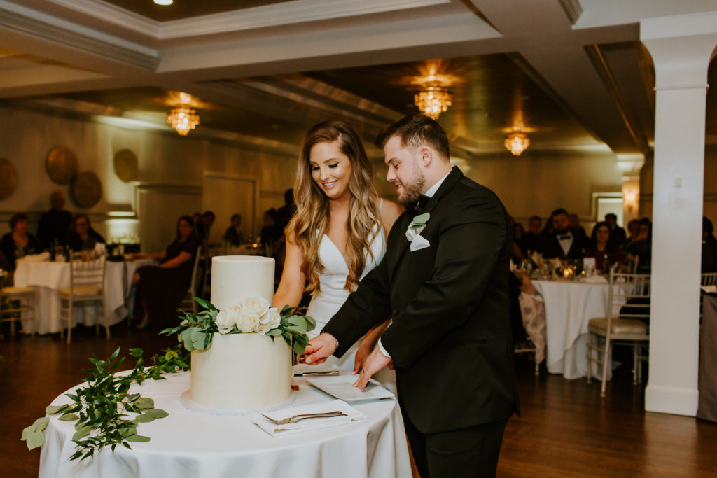Bride and groom cut the cake during reception inside Saphire Estate in Sharon, Massachusetts