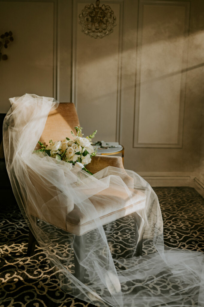 Wedding details showcasing veil and wedding bouquet details inside sunlit bridal suite at Saphire Estate in Sharon, Massachusetts