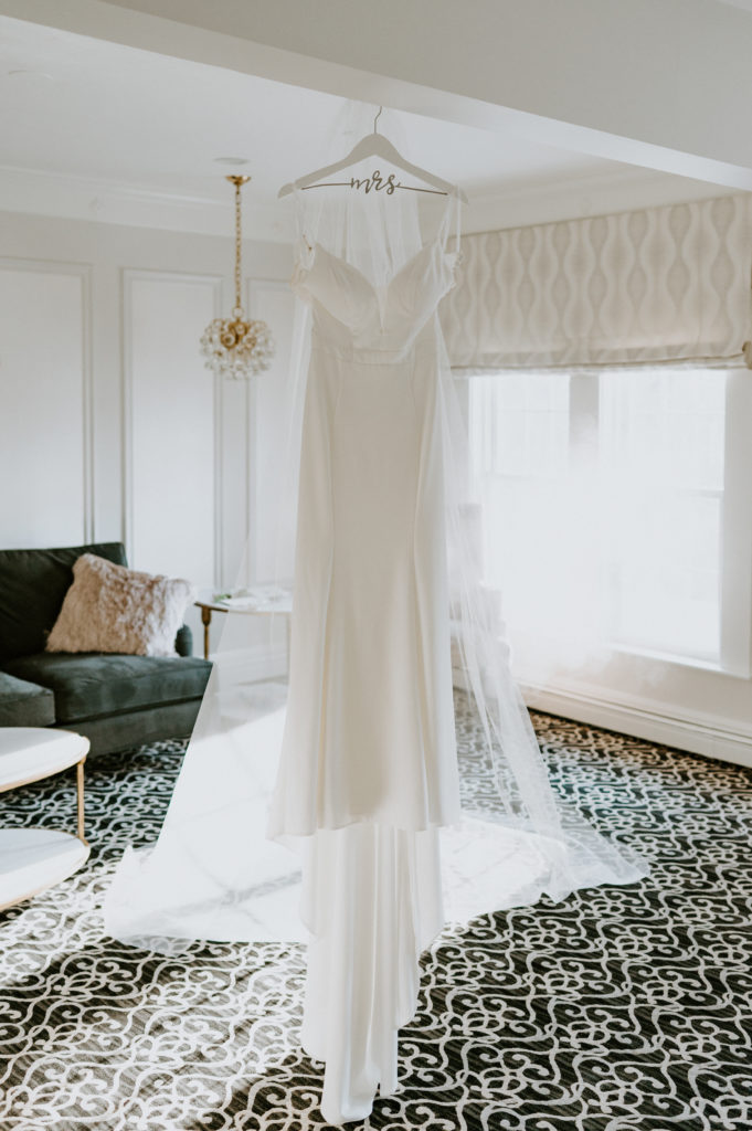 Wedding details showcasing bridal dress on personalized hanger inside bridal suite at Saphire Estate in Sharon, Massachusetts