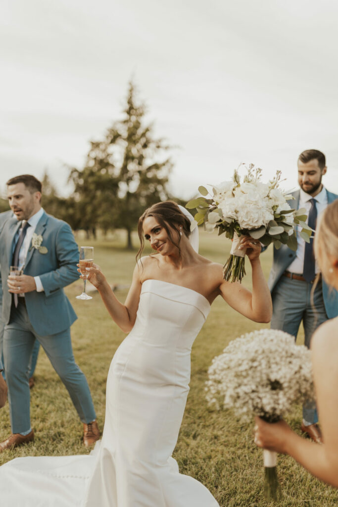 Bride holding champagne and bouquet