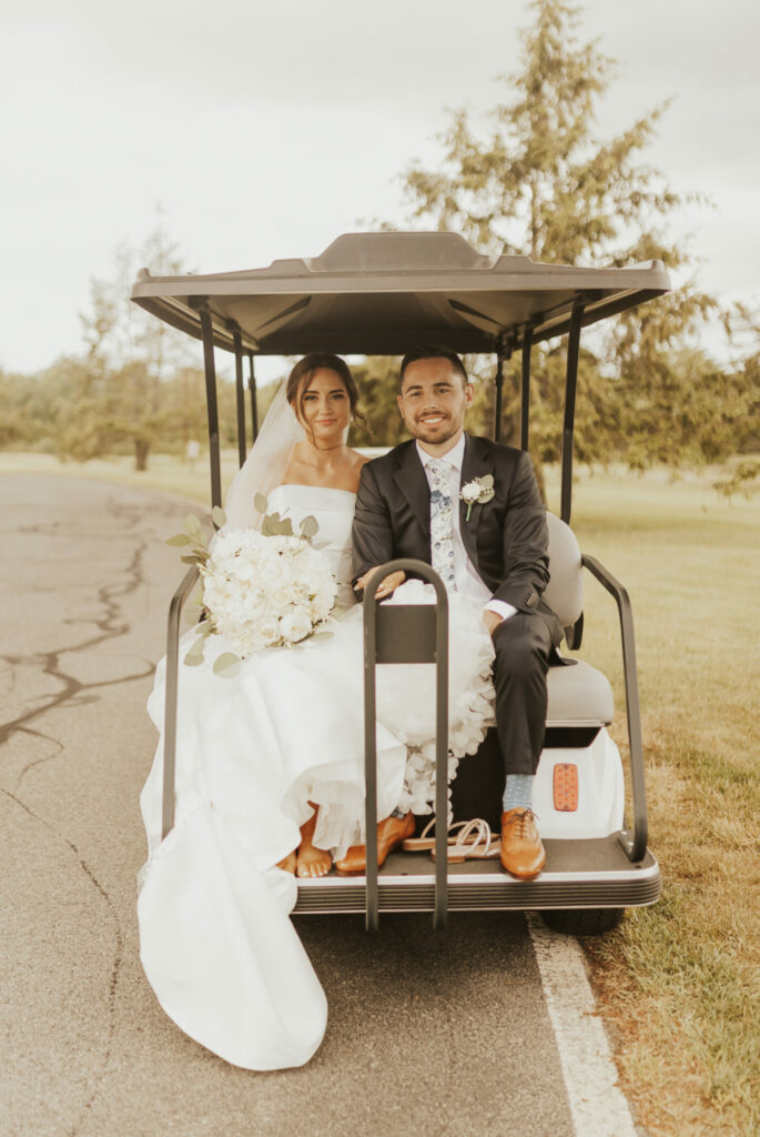 Bride and groom travel the grounds of The Villa in East Bridgewater, Massachusetts by golf cart