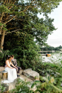 Bride and Groom Sit Near Lake Massapoag in Sharon Massachusetts