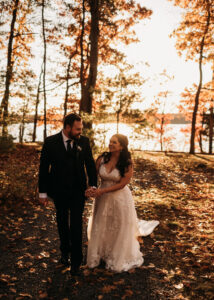 Bride and Groom Walk Through the Woods in the Fall at Saphire Estate