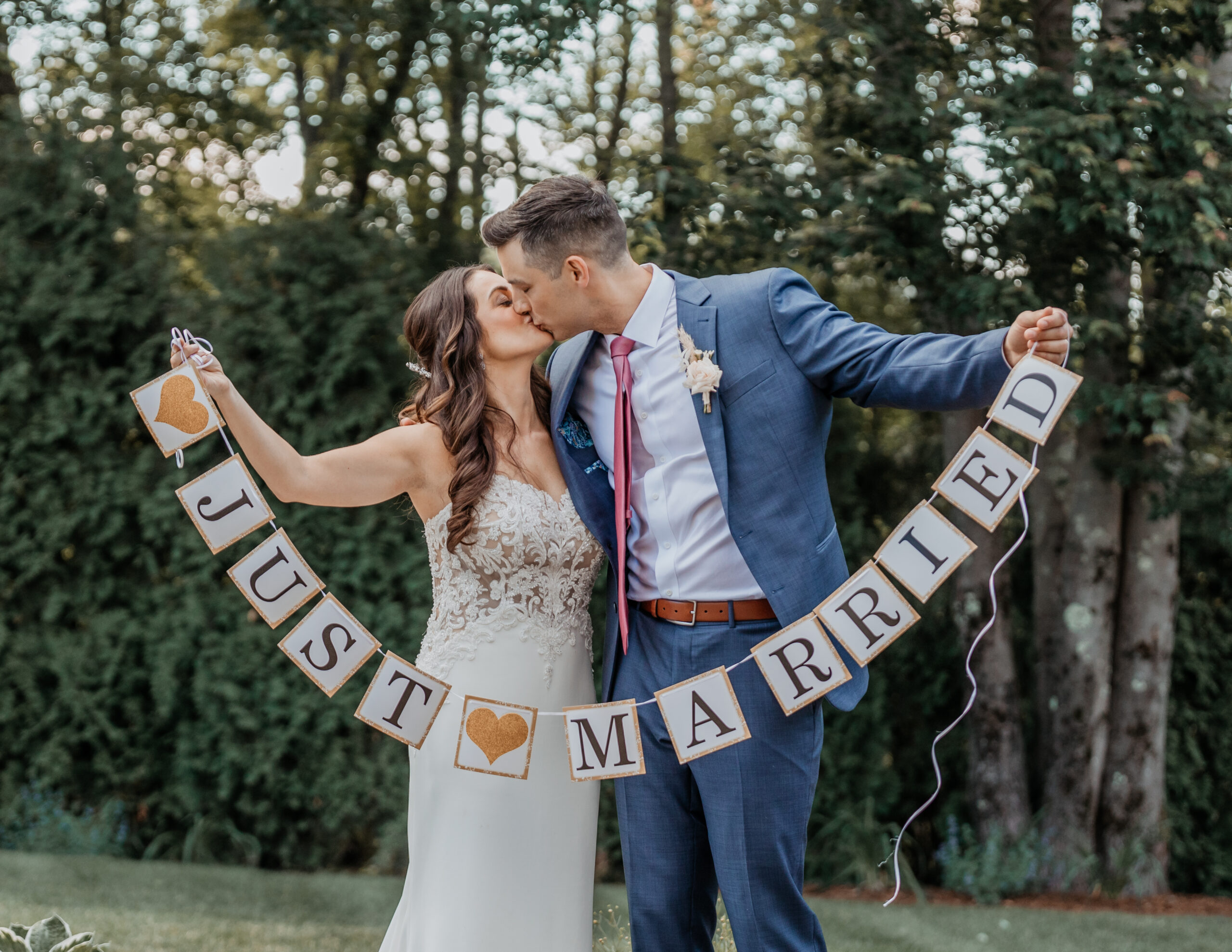 Bride and groom holding a Just Married banner at a wedding venue