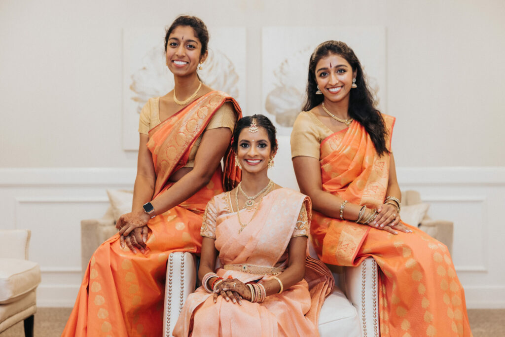 Bride in Peach Sari and Bridesmaids in Orange Saris Sit in the Wedding Suite at Avenir