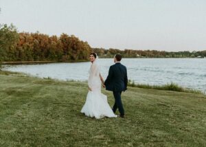 Bride and Groom Walk Along Lake at their Waterfront Wedding at The Lakehouse in Halifax Massachusetts