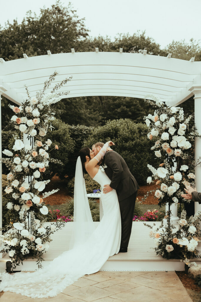 Bride and Groom First Kiss Under Pergola
