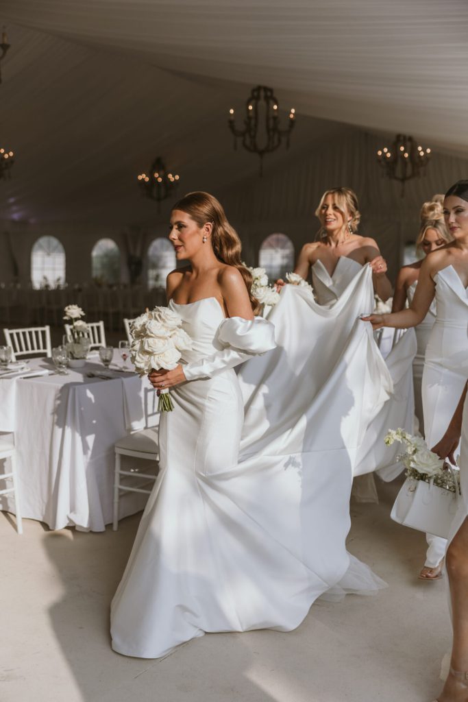 Bridal Party Carrying Train Through Tent