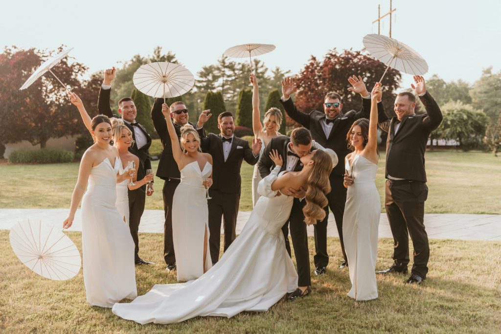 Bride and Groom Kiss in Front of Cheering Wedding Party