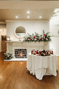 Sweetheart Table in Front of Historic Estate Fireplace With Red and White Florals 