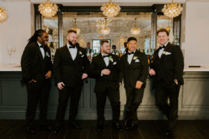 Groomsmen Standing in Front of Cocktail Space Bar and Chandeliers 