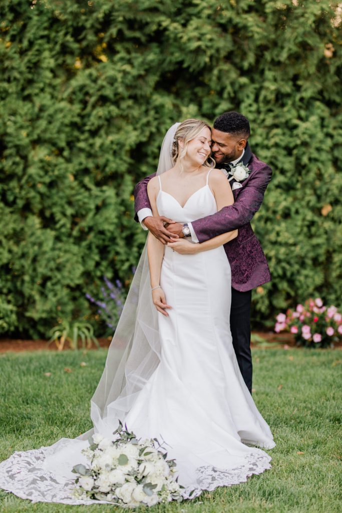 Bride and Groom Portrait Against Greenery Embracing
