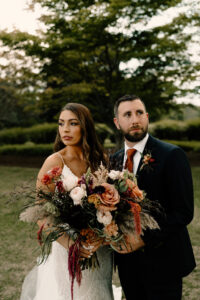 Bride and Groom with Orange and Green Florals Dark and Moody Portrait