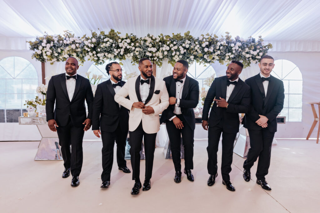 Groom and Groomsmen In Front of White Floral Display