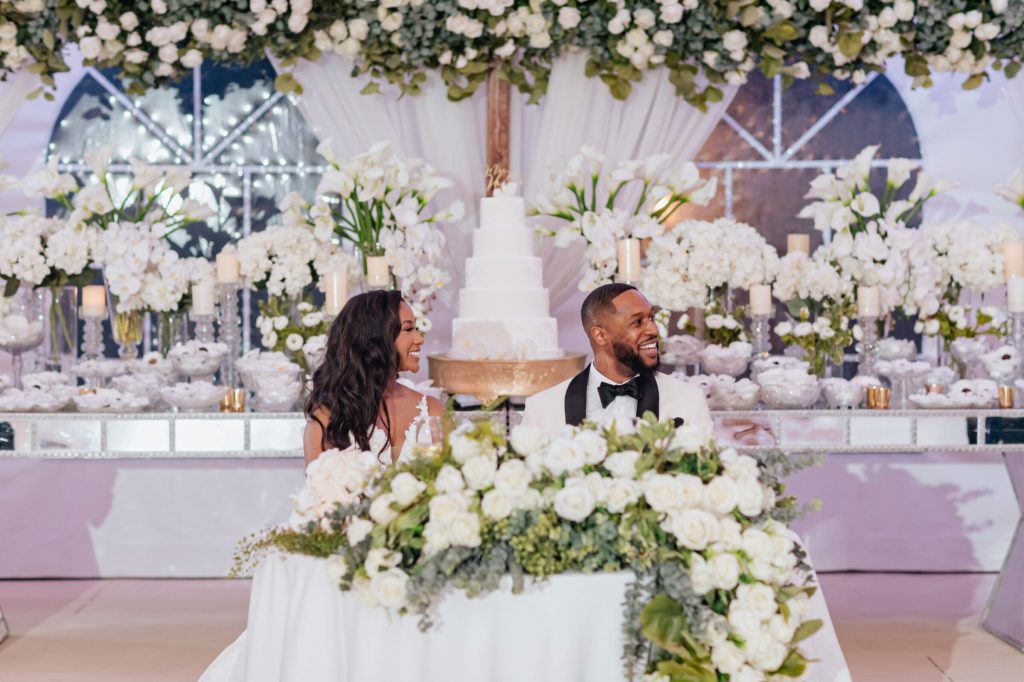 Bride and Groom Sitting at Sweetheart Table Classy and Timeless White Floral Decor