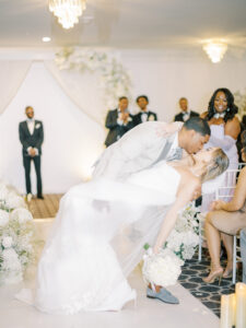 bride and groom dip kiss at indoor wedding ceremony