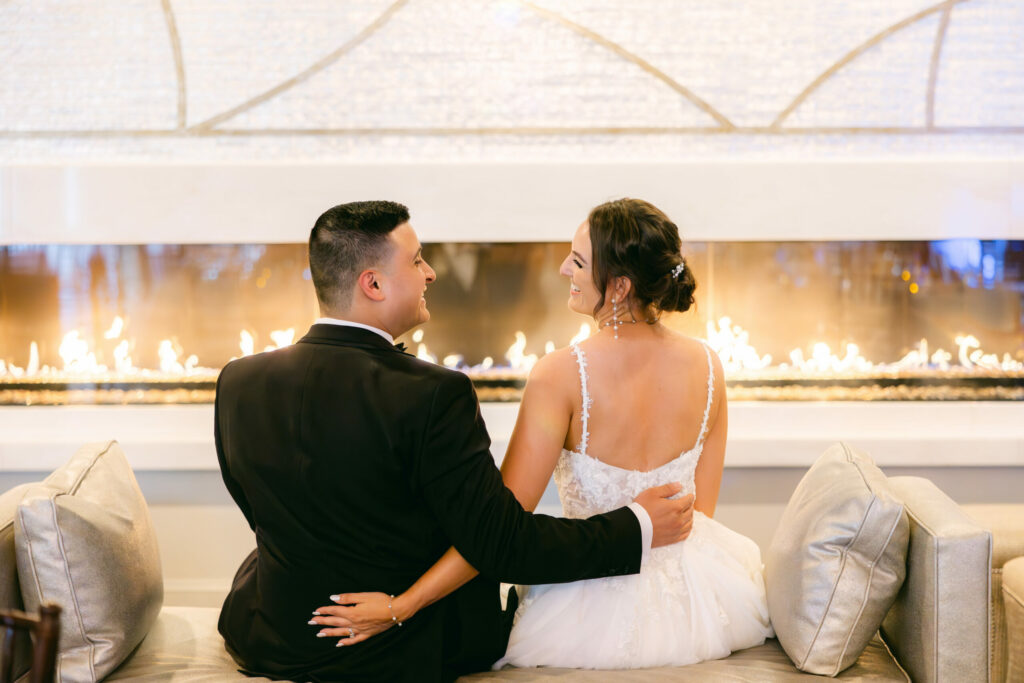 bride and groom sitting in front of fireplace at saphire event venue