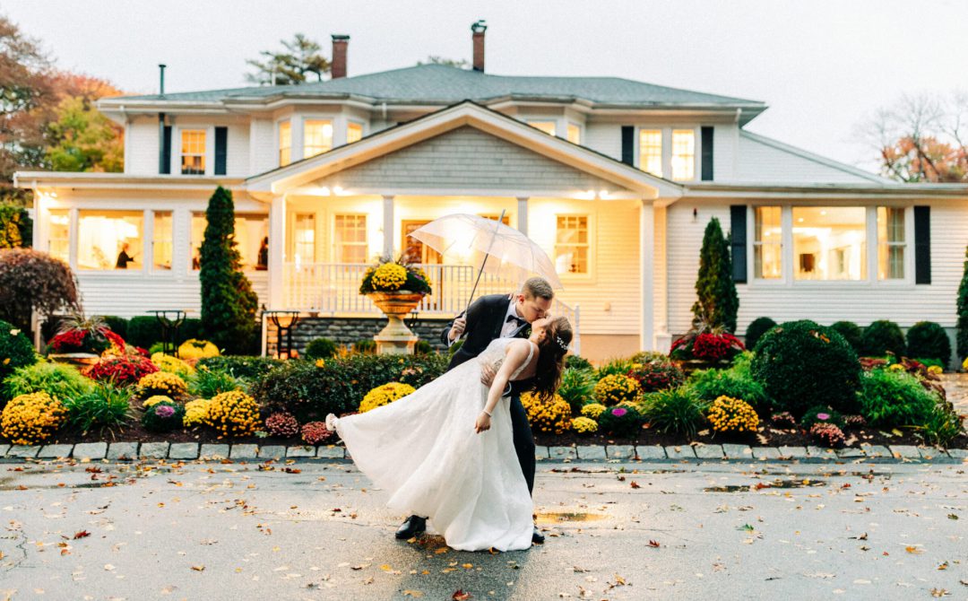 Bride and Groom dip Kiss in Front of Glowing Saphire Estate