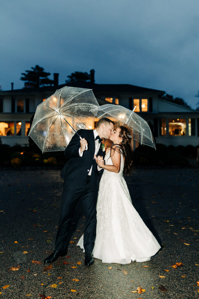 Bride and Groom Kiss at Night Under Umbrella in Front of Saphire Estate