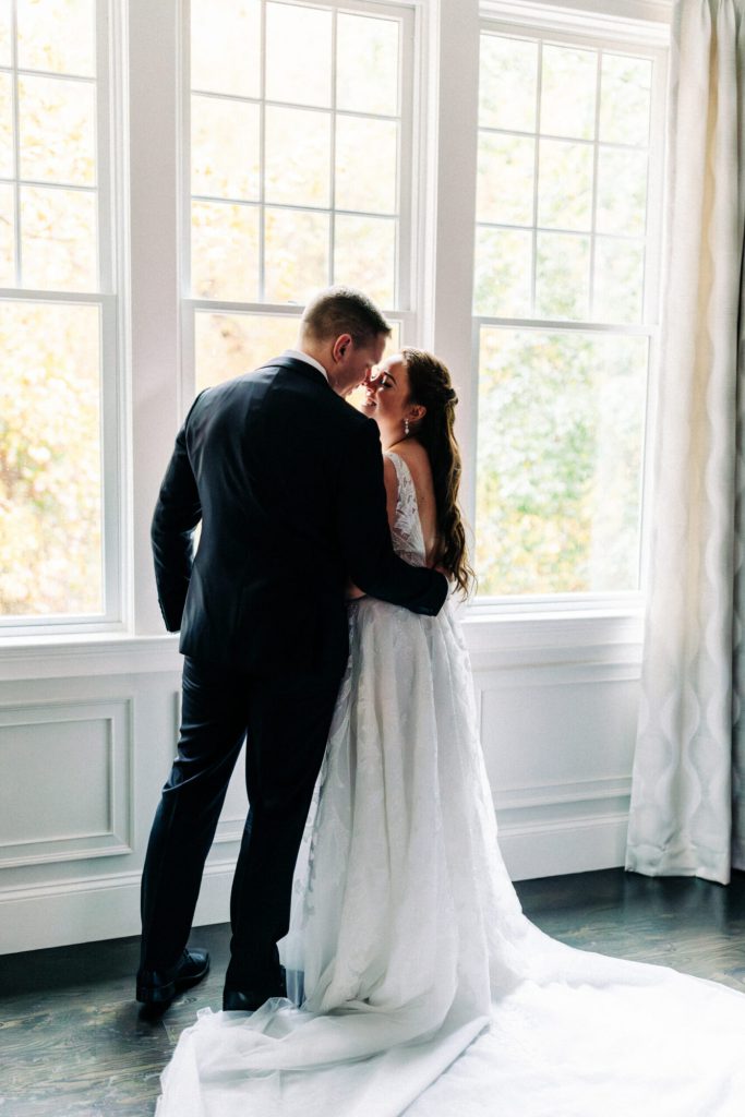 Bride and Groom Stand in Front of Saphire Estate Cocktail Space Window