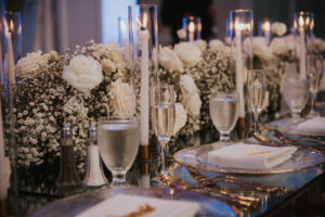 Table setting with votive candles, white roses, and baby's breath.