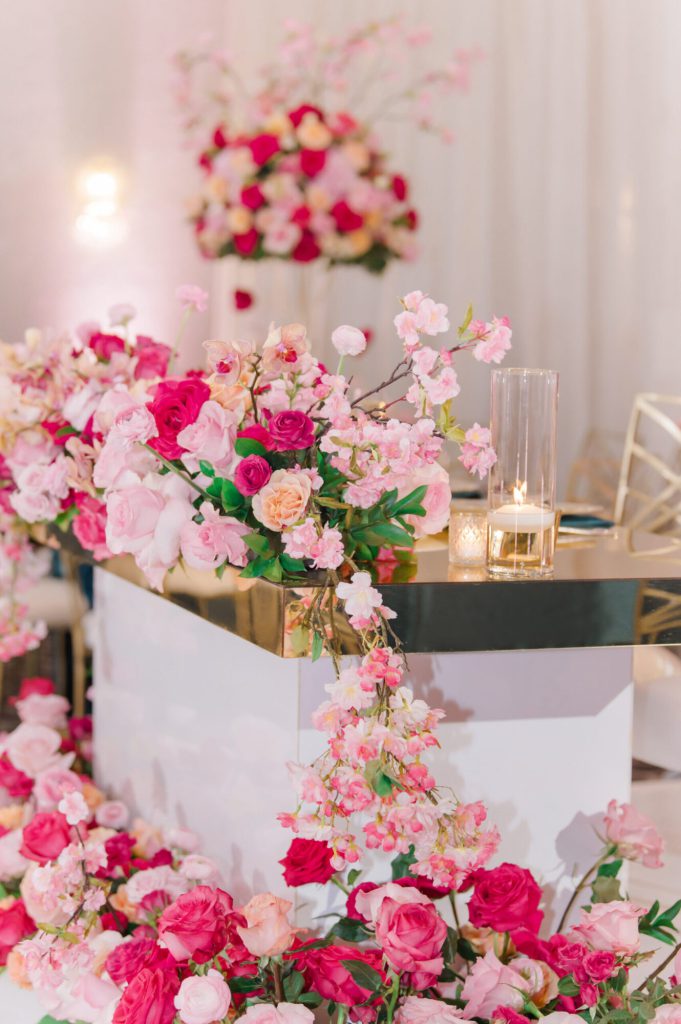 Sweetheart table framed by cascading pink and white roses.
