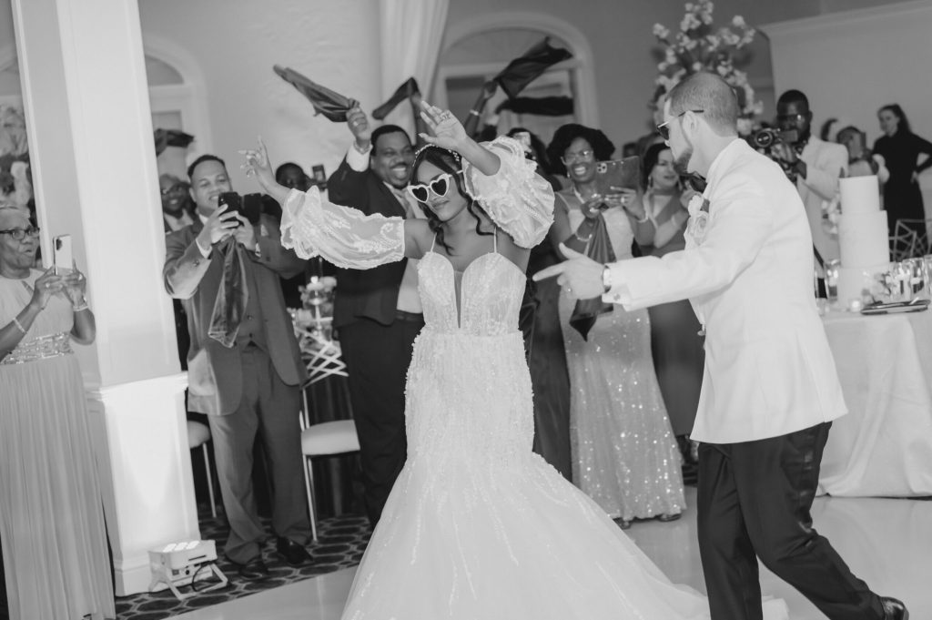 Black and white photo of the bride and groom dancing among guests.