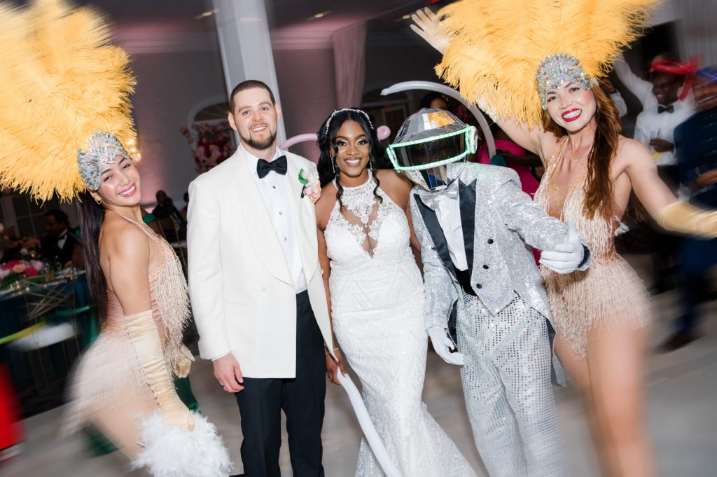 Bride and groom posing with costumed performers in feather headdresses.