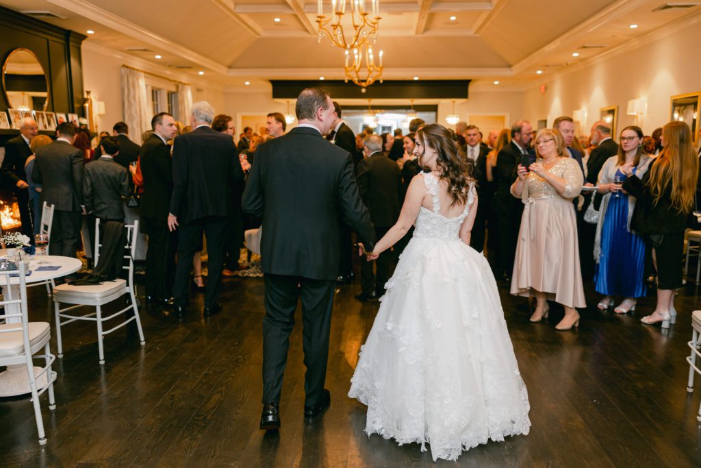 Bride and groom walking through guests in the reception room.