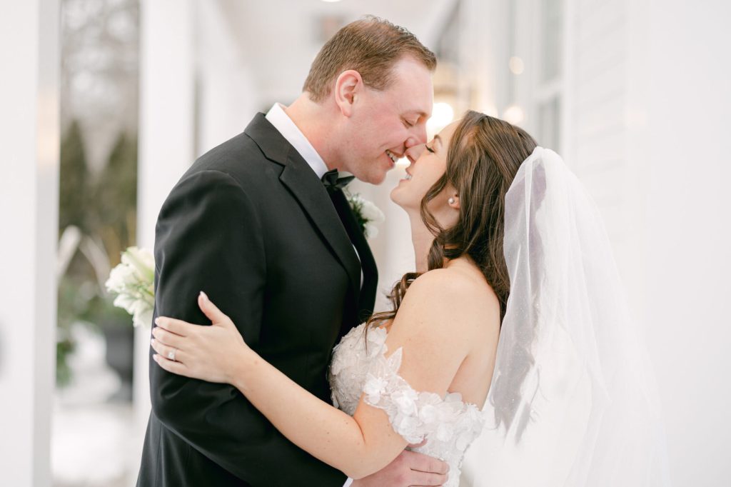 Bride and groom kissing in soft window light.