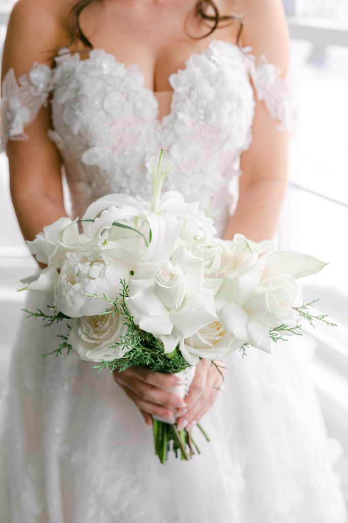 Bride holding a bouquet of white roses and calla lilies.