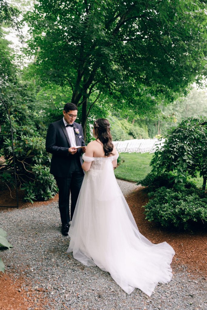 Bride approaching the groom on a garden path for their first look.