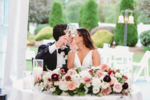 bride and groom cheers at sweetheart table at all-inclusive wedding reception