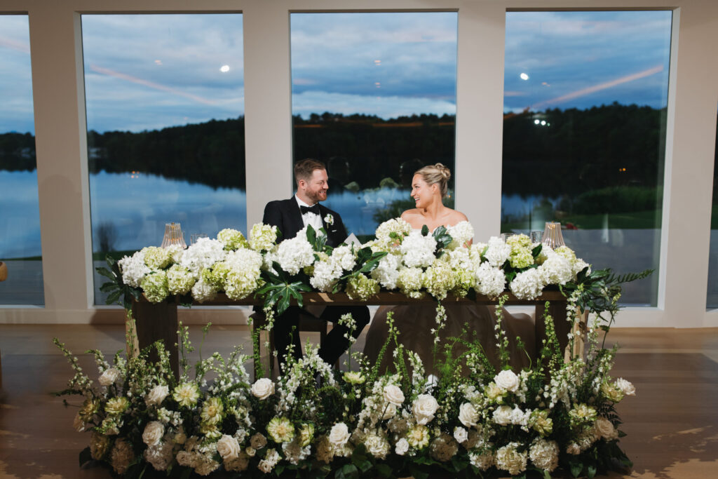 Bride and groom at green and white floral sweetheart table